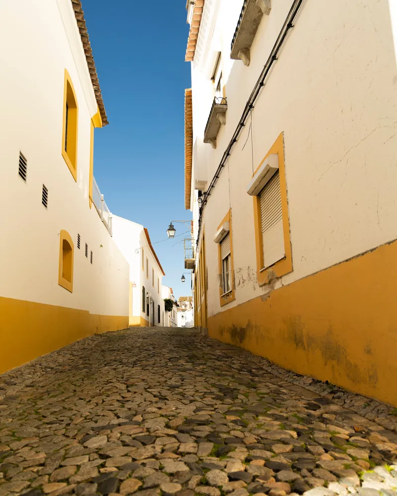 Rua de casas brancas com barra amarela em Évora