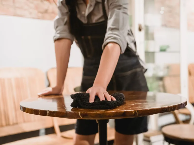 Profissional a limpar a mesa de um café